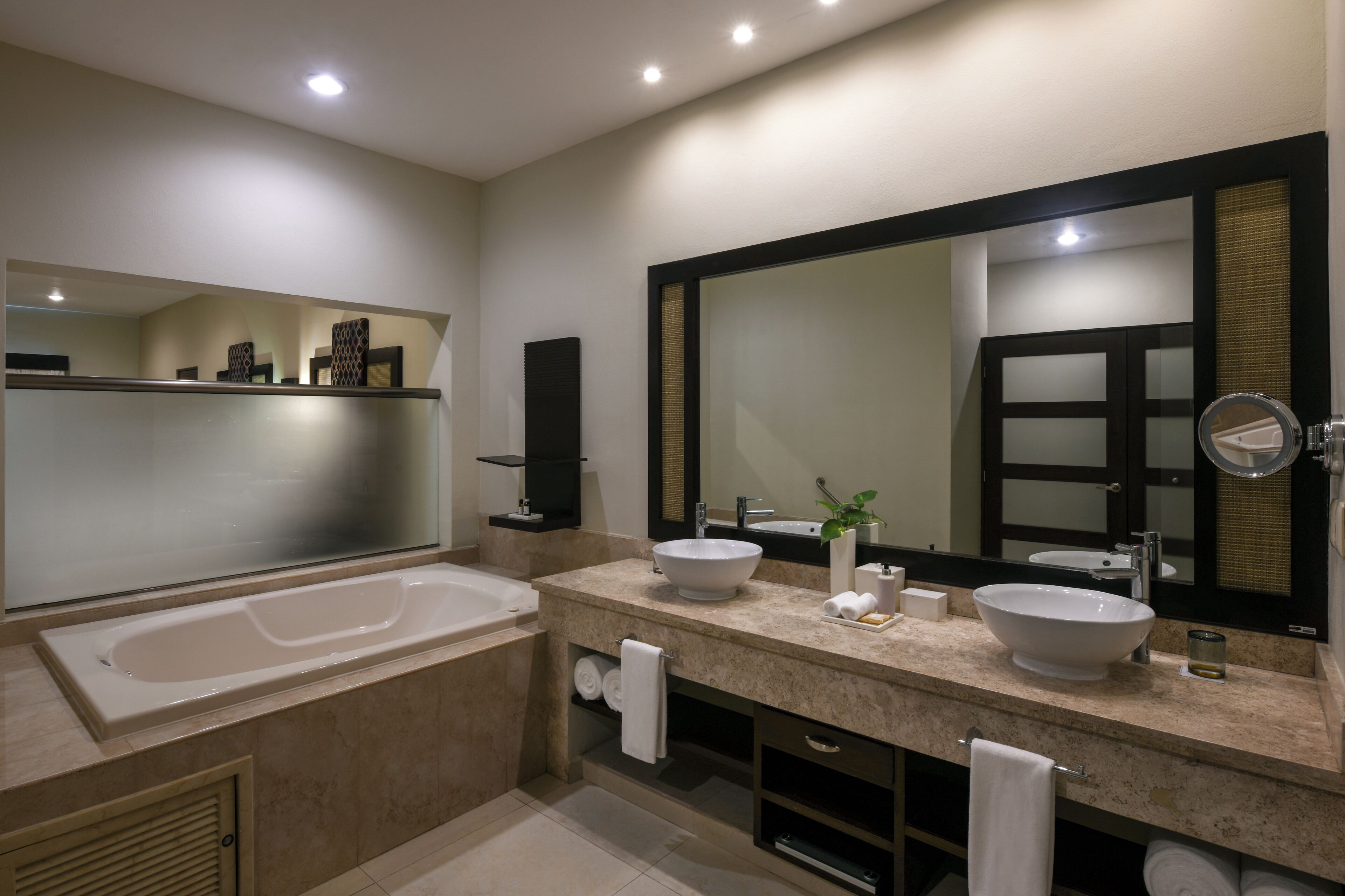 Un baño moderno con una bañera grande, dos lavamanos, un espejo amplio y un perchero para toallas.