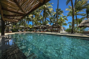 A clear pool with lounge chairs and umbrellas, surrounded by palm trees and a thatched-roof structure. - El Dorado Maroma, All & More Inclusive - Adults Only (Playa del Carmen)