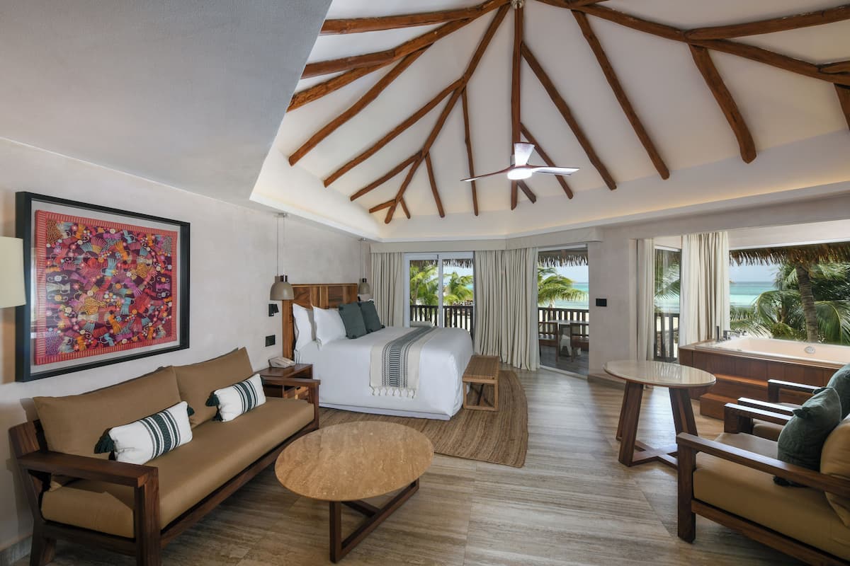 Een hotelkamer met een bed, een bank, een bijzettafeltje en uitzicht op de oceaan.