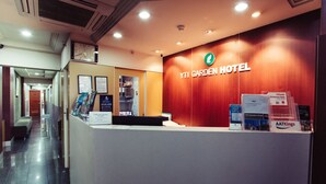 A reception desk at YTI Garden Hotel with a wooden wall, a clock, and informational brochures. - YTI Garden Hotel (Melbourne)