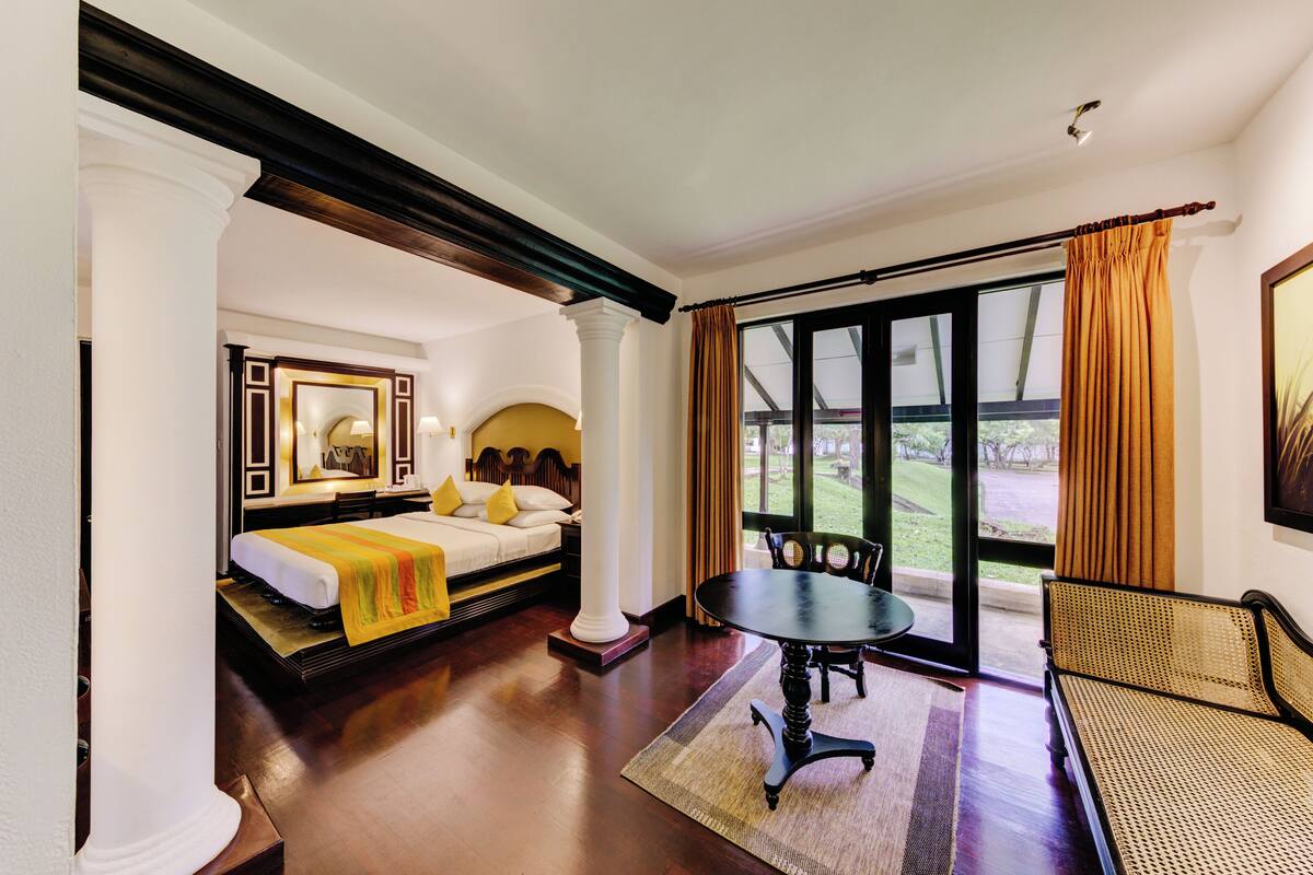 A hotel room with a bed, a dining table, and a view of the outdoors.