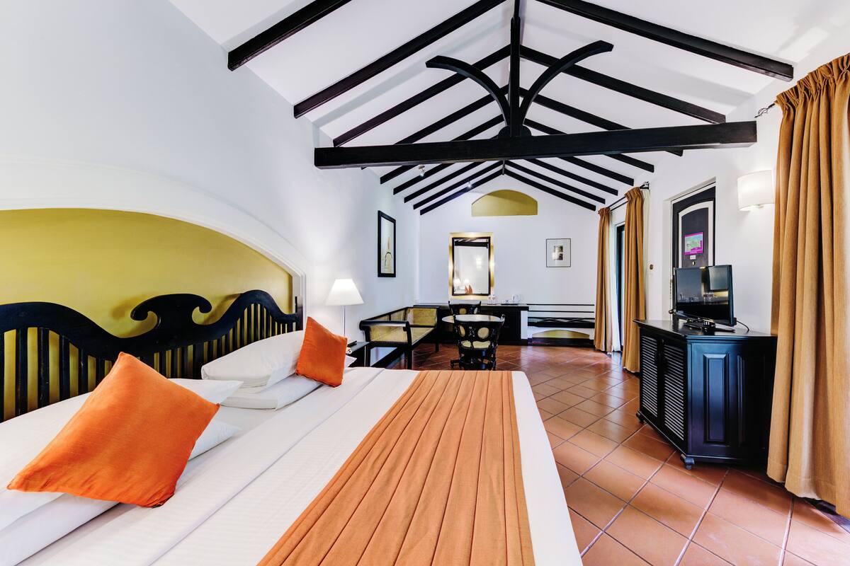 A hotel room with a bed, a desk, a television, and a bathroom visible in the background.