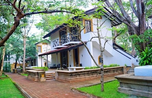 A two-story building with a balcony, surrounded by greenery and a brick pathway. - Cinnamon Lodge (Habarana)