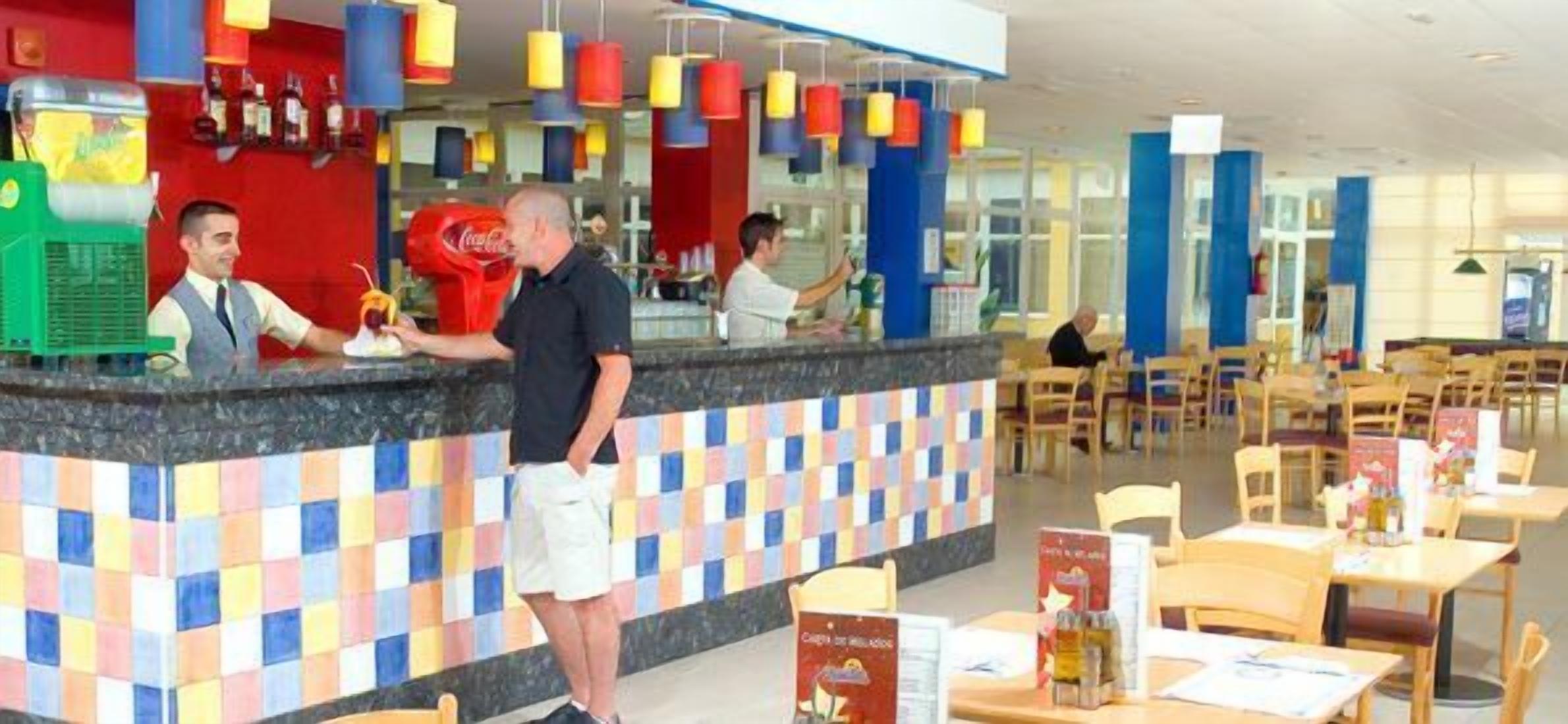 A buffet area with a counter, seating, and a Coca-Cola refrigerator.