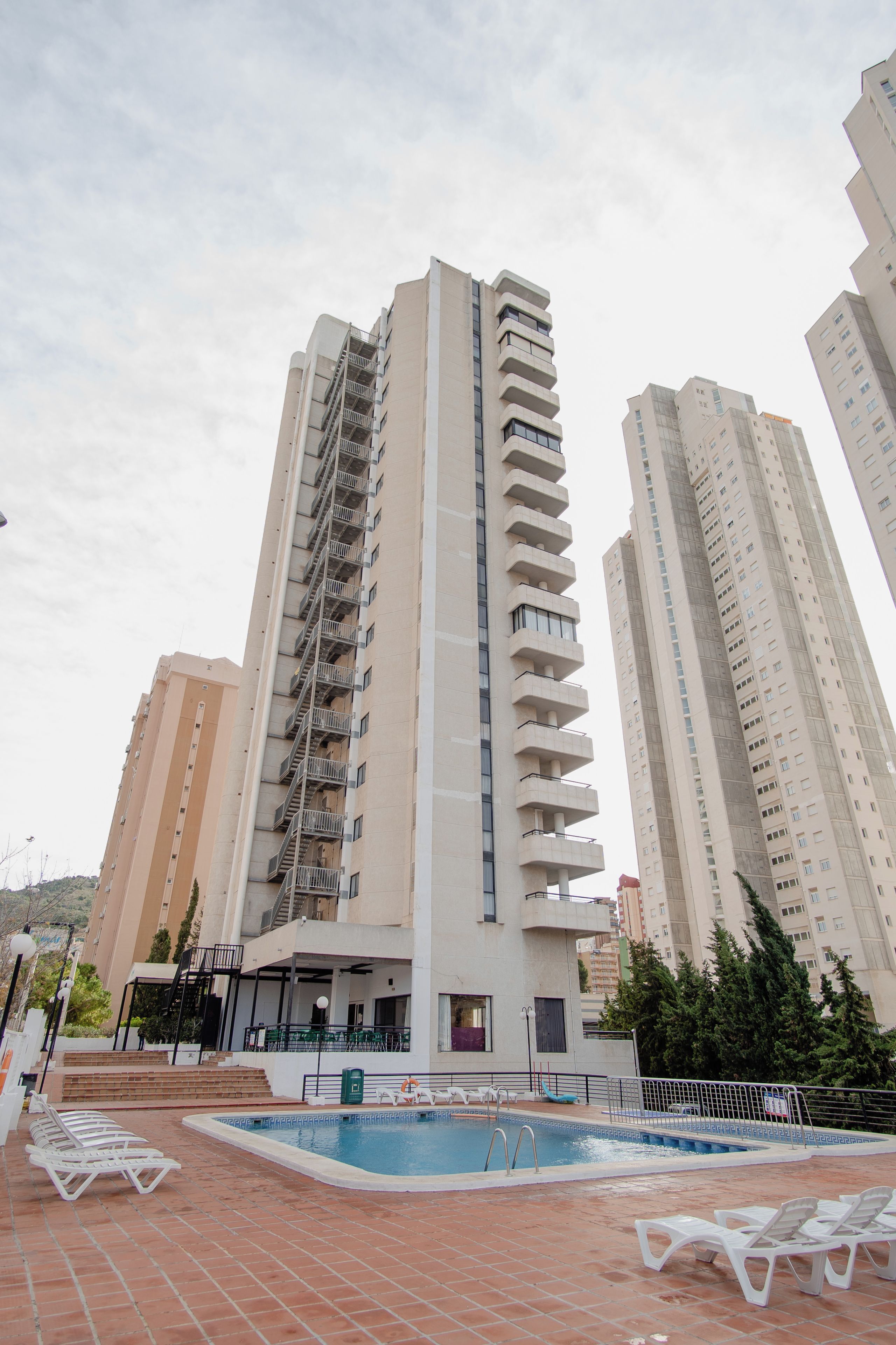 A high-rise residential building with a swimming pool and sun loungers.