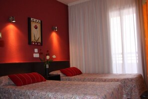 A hotel room with two beds, a red wall, a framed picture, and a window with curtains. - Luxmar Apartments by MC (Benidorm)