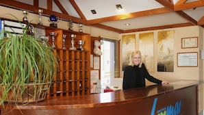 Una mesa de recepción con un letrero que dice "apert-hotel luxmai" y una mujer parada detrás.