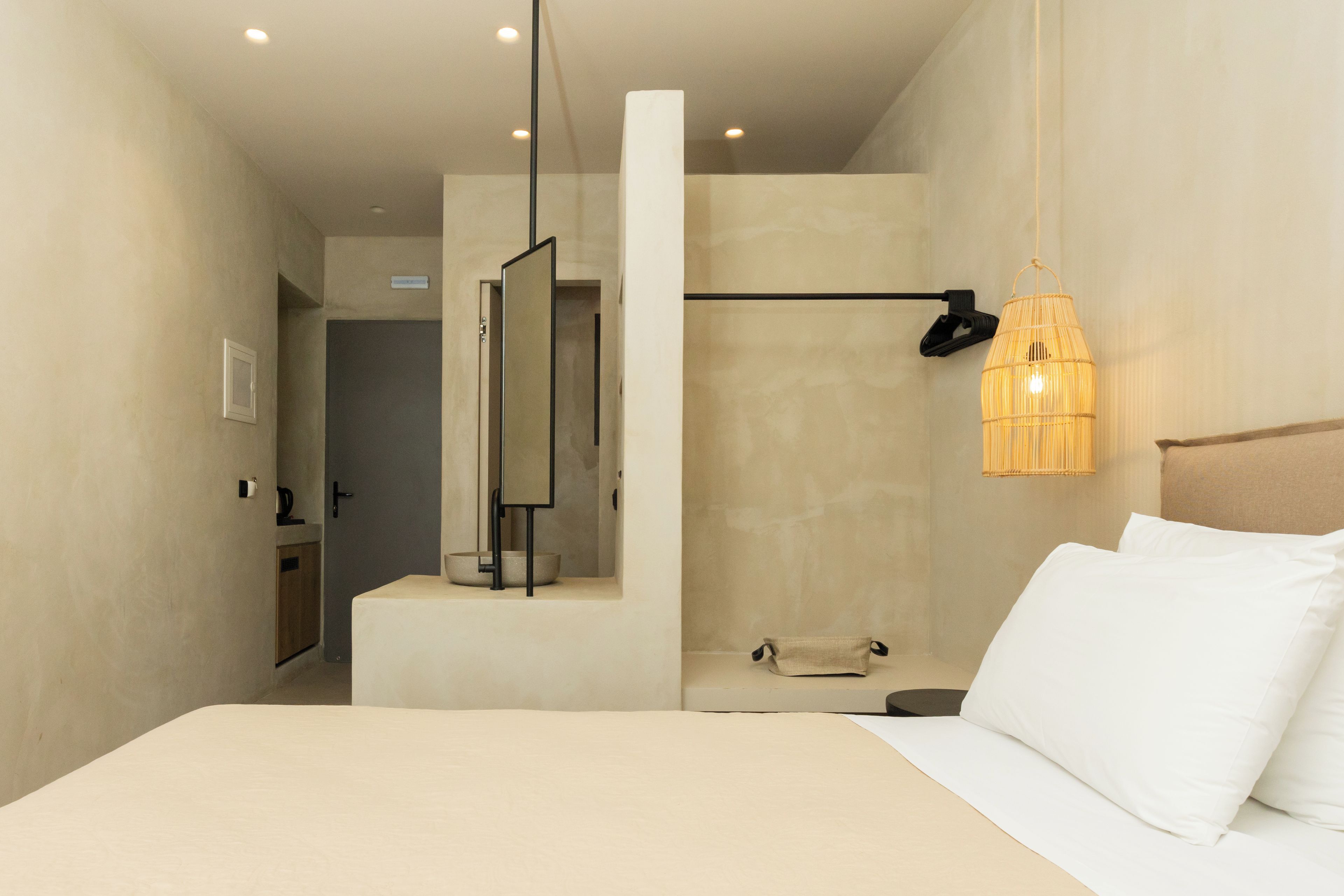 Ein modernes Hotelzimmer mit Bett, Duschbereich und Spiegel.