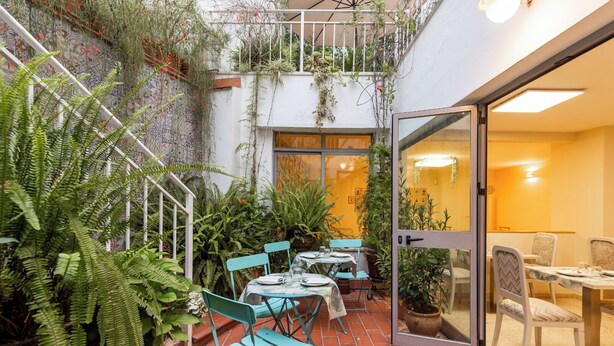 A patio area with tables and chairs, surrounded by potted plants and greenery. - Colectia Hotel Santa Lucia (Seville)