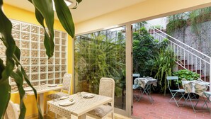 A dining area with a glass door leading to a garden, a tiled wall with a geometric pattern, and a staircase with a patterned railing. - Colectia Hotel Santa Lucia (Seville)