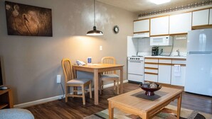 Un espace de vie compact comprenant un coin repas, une kitchenette et un tableau accroché au mur.