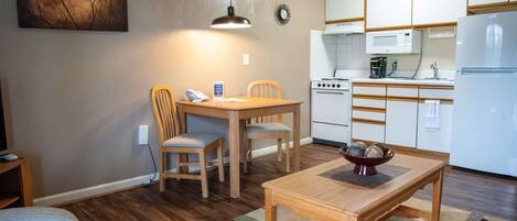 A compact living space with a dining area, kitchenette, and a painting on the wall.