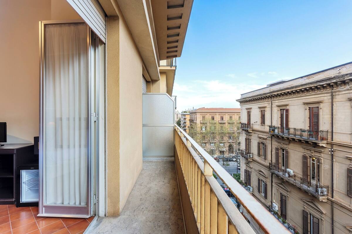 A balcony with a view of adjacent buildings, a door, and a small table.