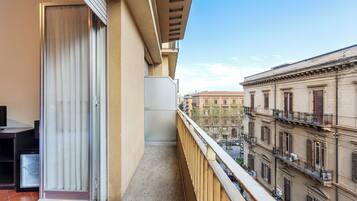A balcony with a view of adjacent buildings, a door, and a small table.