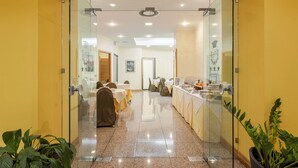 A hotel lobby with a glass partition, a reception desk, and a dining area with tables and chairs. - Crisol Europa (Palermo)