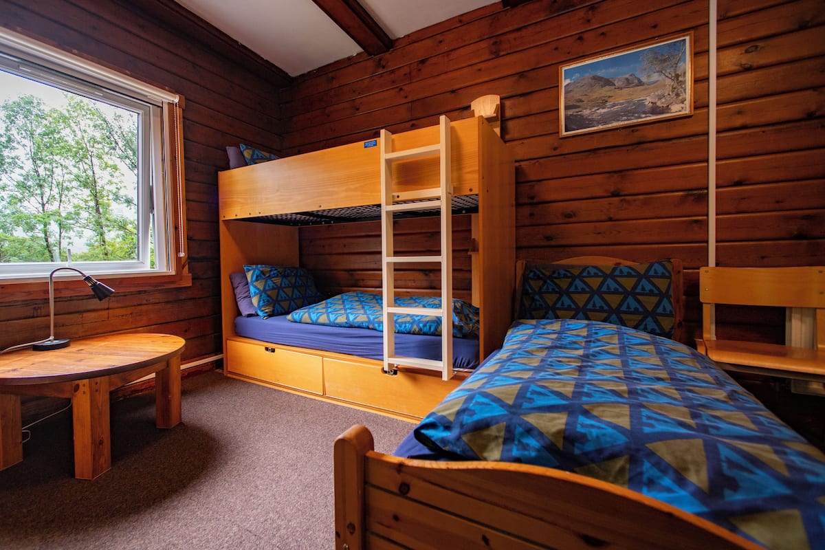 A cabin with a bunk bed, a desk, and a window.