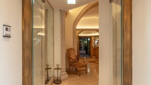 Entrada de un hotel con suelo de mármol, mostrador de recepción y una silla al fondo.
