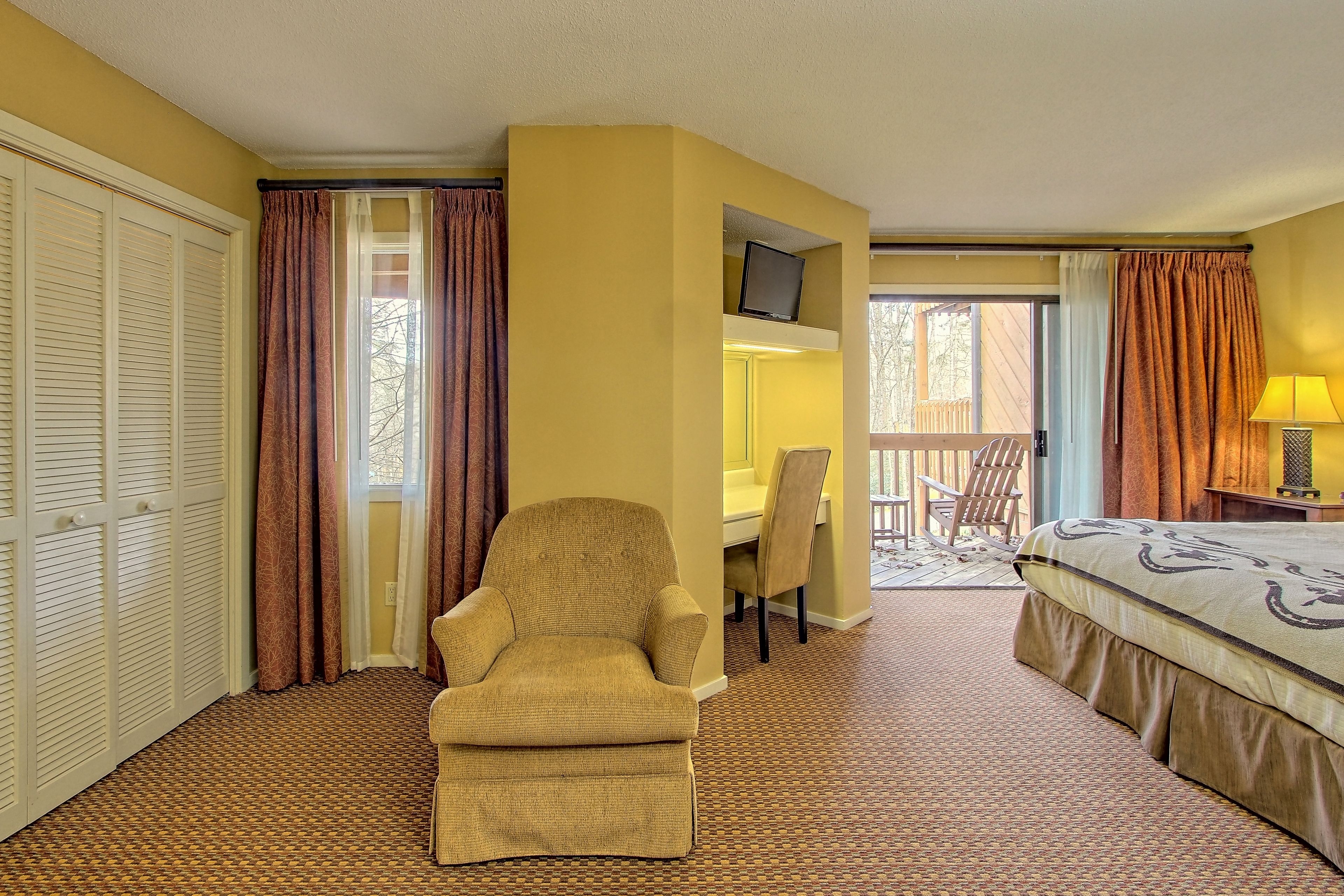 Habitación de hotel con cama, silla, escritorio y televisión.