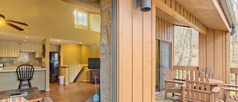 Een houten terras met Adirondack-stoelen en een stenen muur.