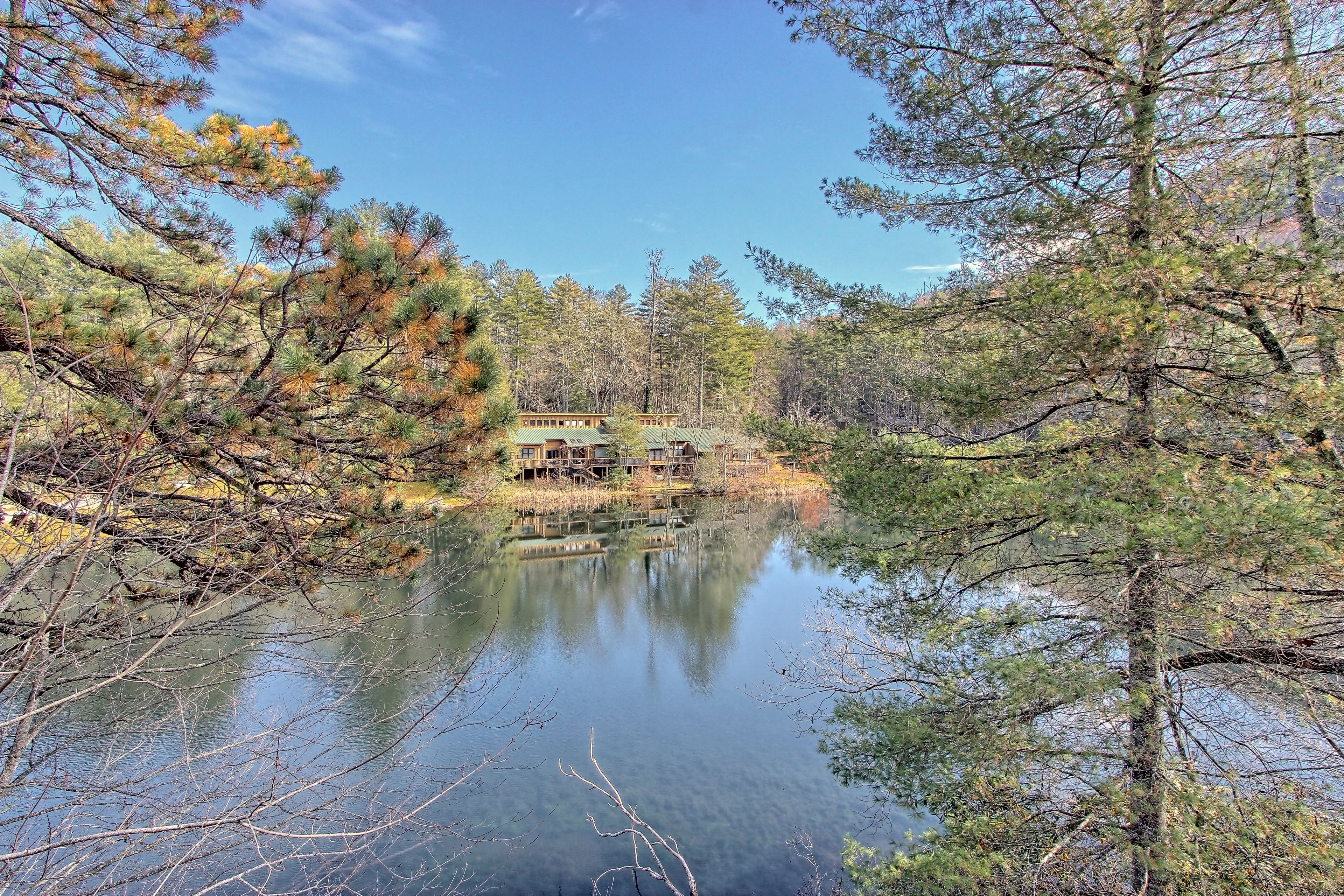 Una cabana amb una vista clara d'un llac envoltat d'arbres.