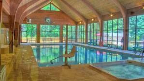 An indoor swimming pool with wooden beams, clear glass windows, and a bench. - Foxhunt at Sapphire Valley (Sapphire)