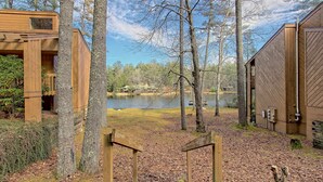A wooden cabin with a staircase leading to a deck overlooking a lake, surrounded by trees. - Foxhunt at Sapphire Valley (Sapphire)