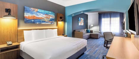 A hotel room with a large bed, a desk, a chair, and a TV.