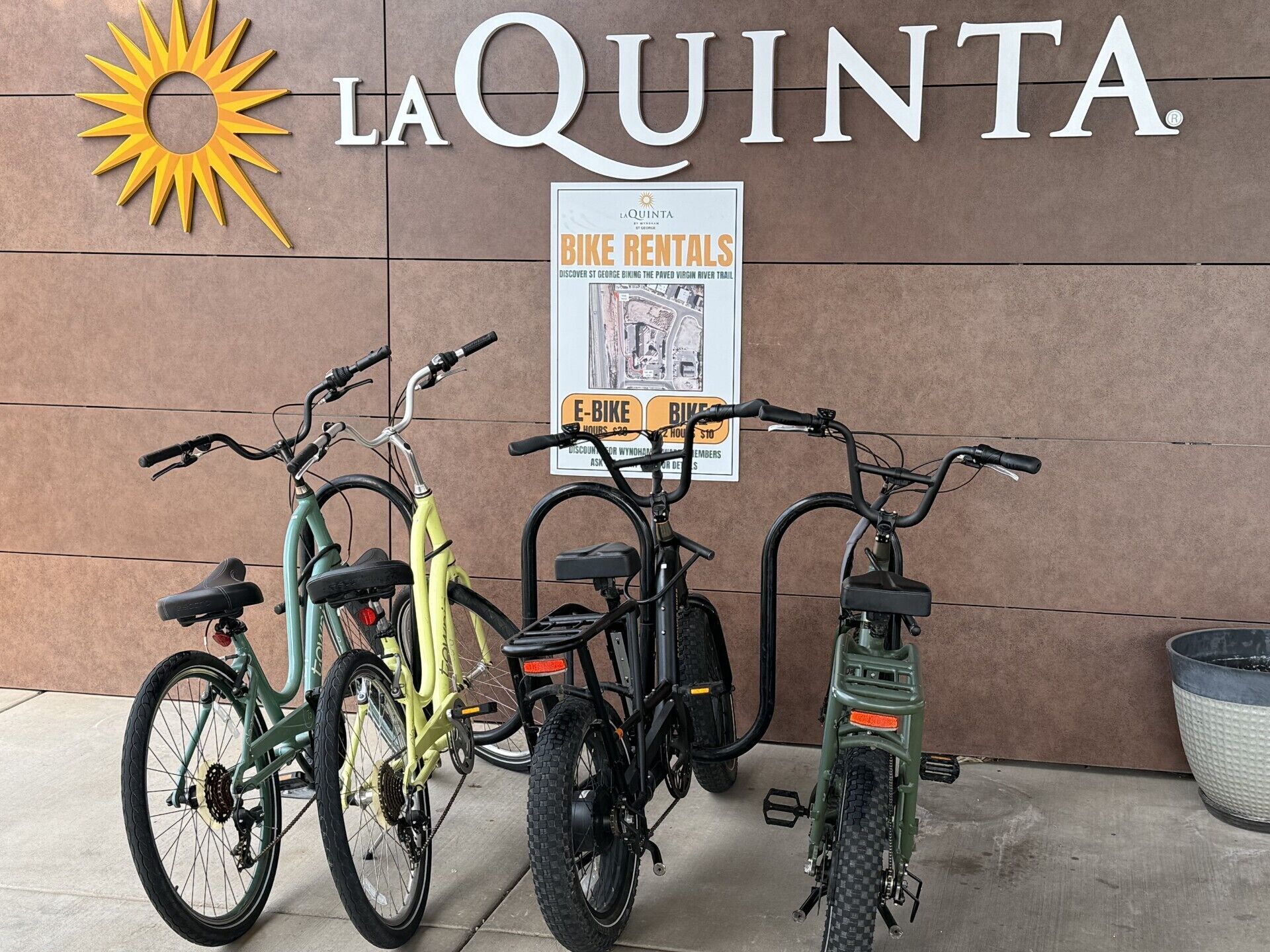 Three bicycles parked in front of a building with a sign advertising bike rentals.