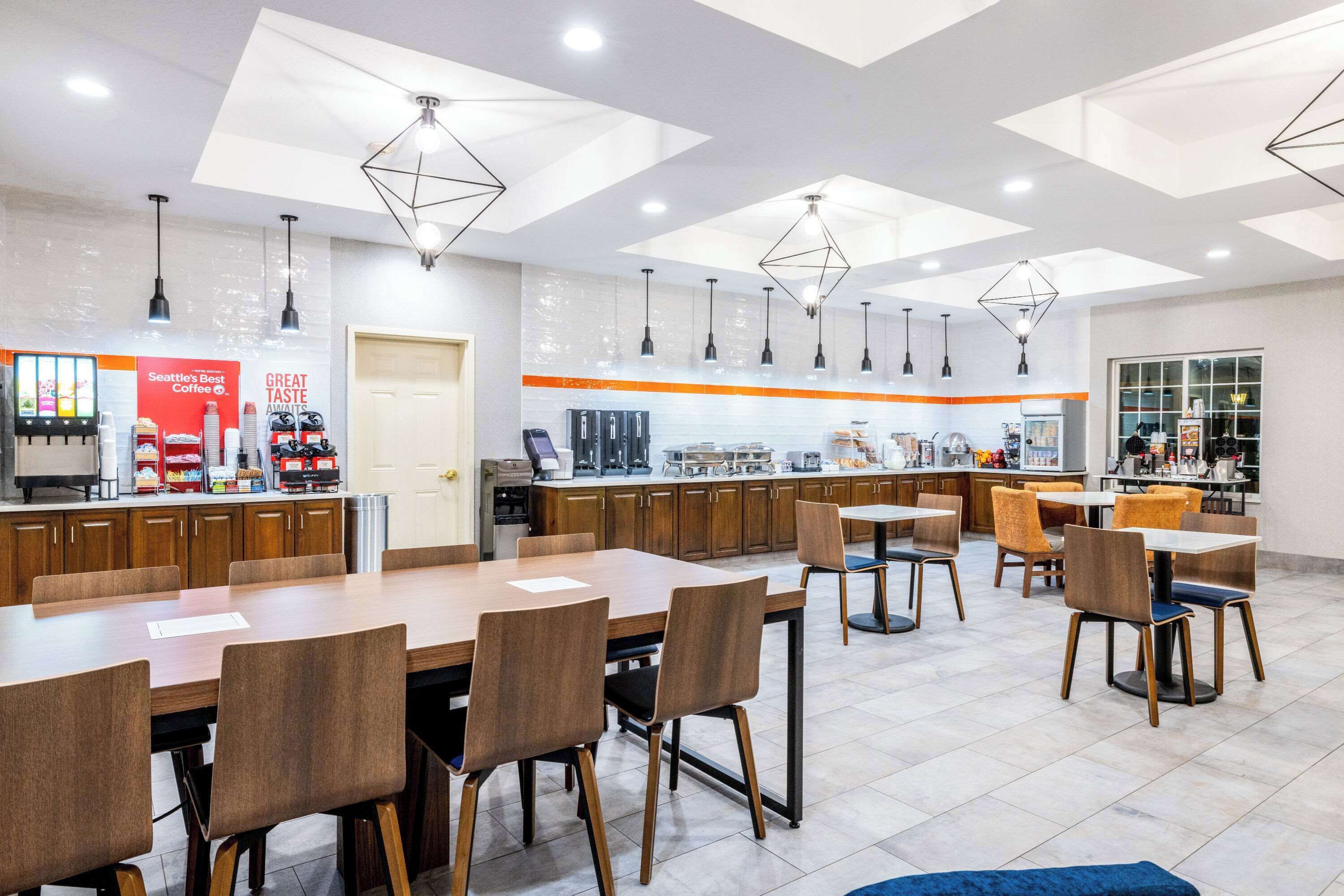 Um café moderno com mesas e cadeiras de madeira, um balcão de café e iluminação pendente.