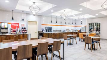 Un café moderne avec des tables et des chaises en bois, un comptoir à café et des luminaires suspendus.