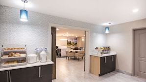 Une chambre d’hôtel moderne dotée d’un buffet de petit-déjeuner, d’un espace repas et offrant une vue sur le paysage urbain.