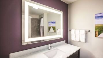 A bathroom with a large mirror, white sink, and two towels hanging on a rack.