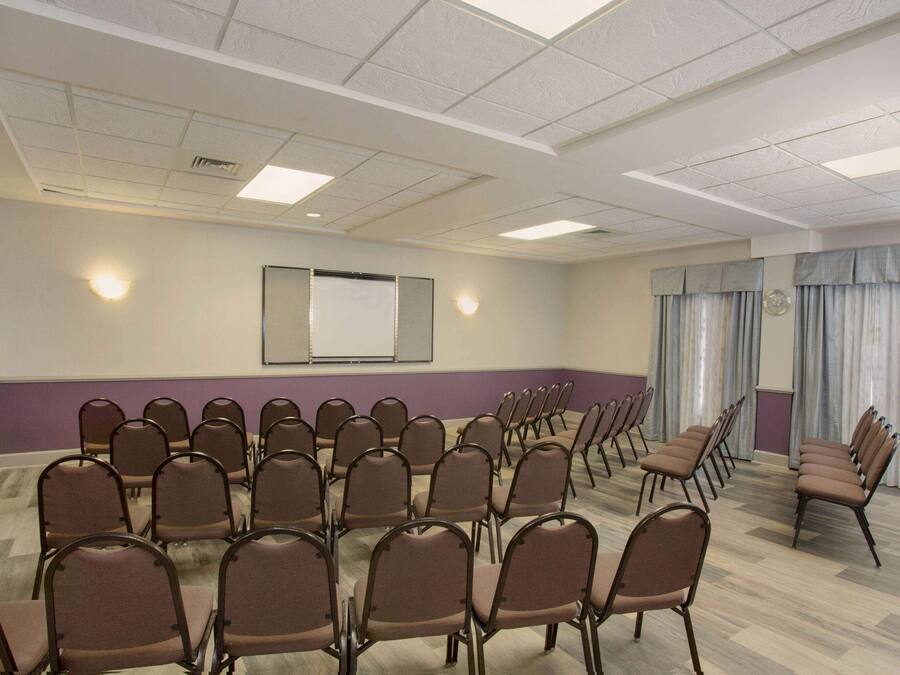 A conference room with rows of chairs, a projector screen, and a whiteboard.
