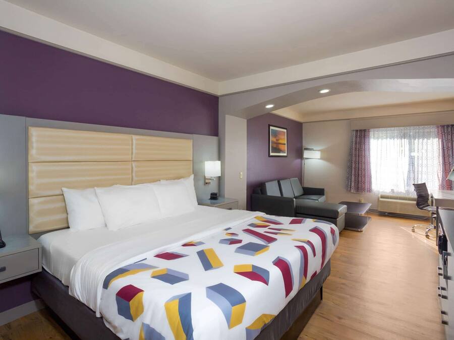 A hotel room with a large bed, a desk, a chair, and a TV.
