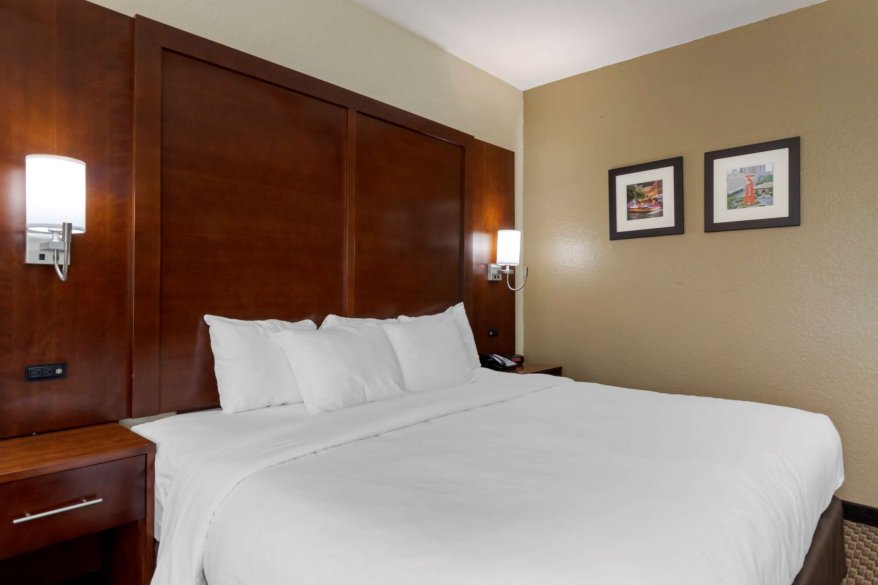 A neatly made bed with white linens in a hotel room.