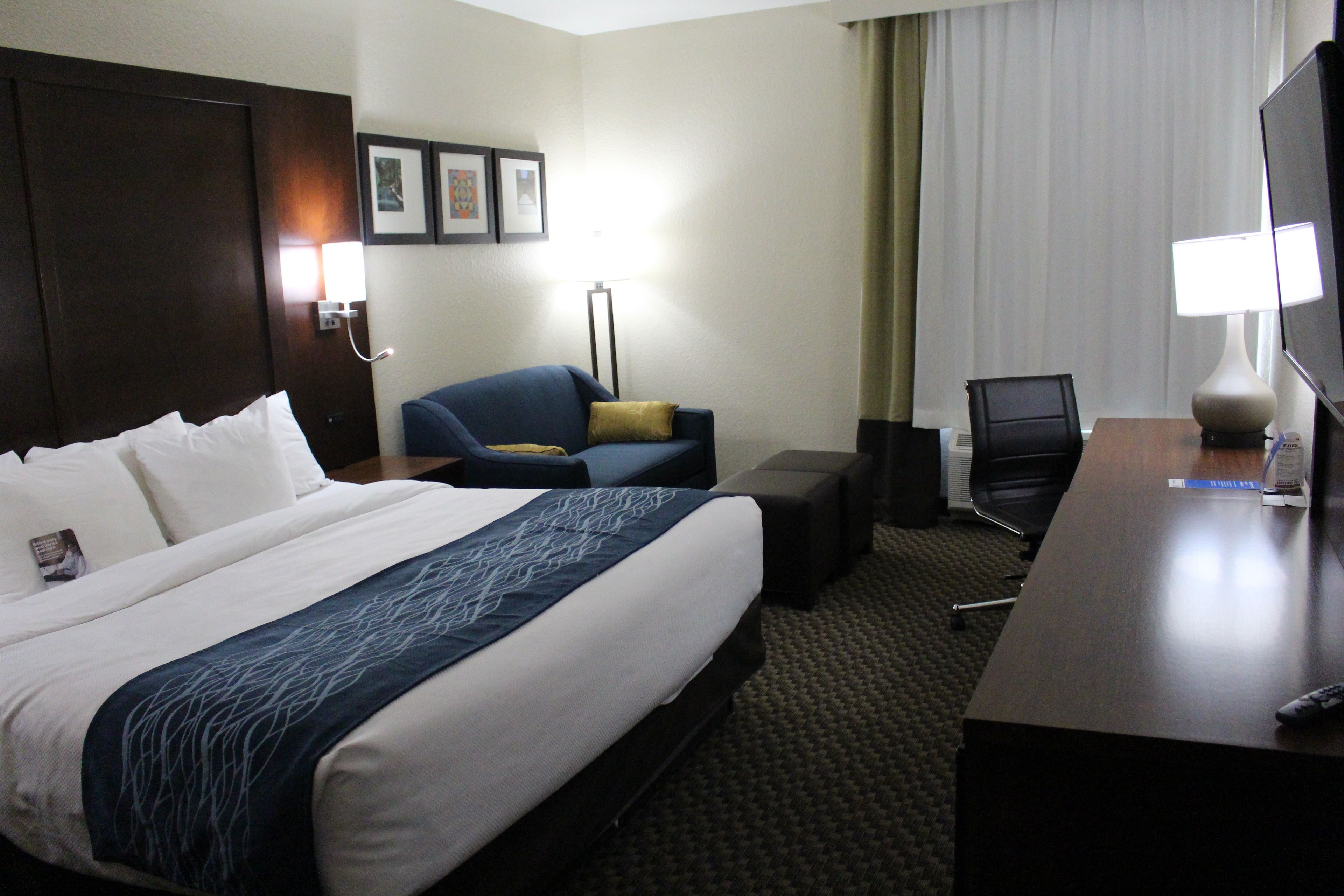 Habitación de hotel con una cama grande, un escritorio, una silla y un televisor.