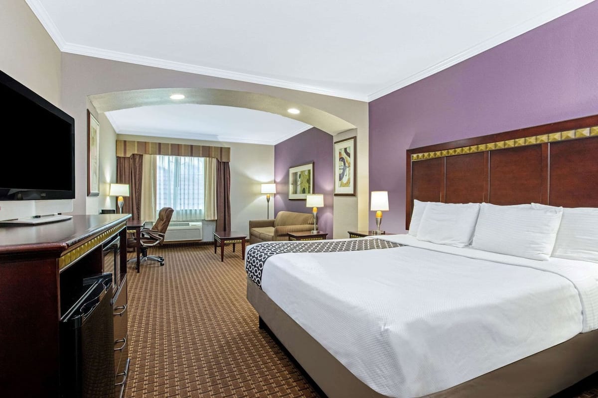 A hotel room with a large bed, a TV, a desk, and a chair.