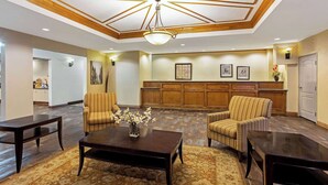 Un hall d’entrée avec un plafond haut, des boiseries, un comptoir d’accueil et un tapis à motifs.