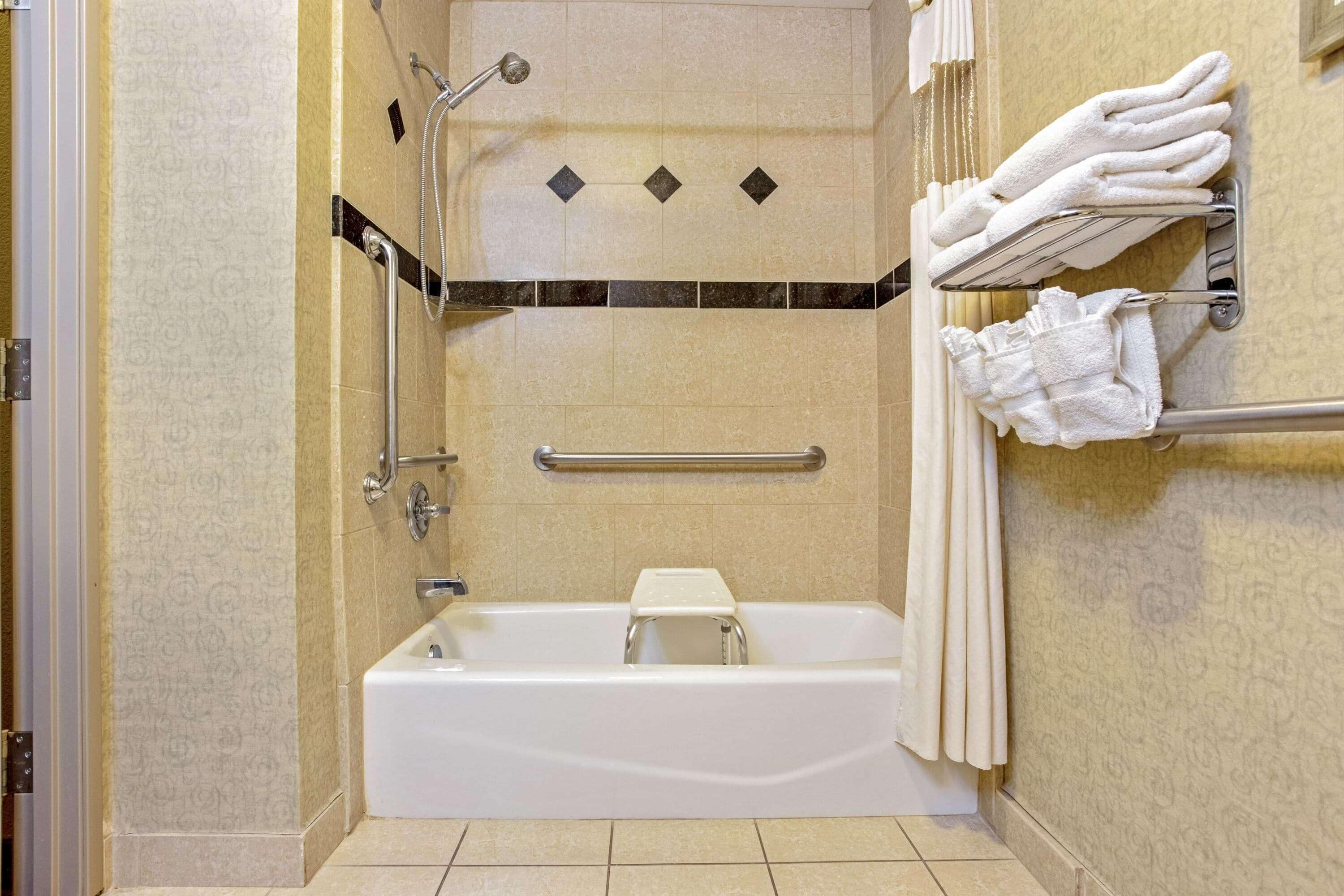 Un baño con bañera, ducha y un perchero con toallas.