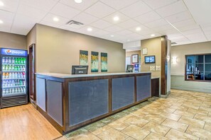 A reception area with a Pepsi refrigerator, a reception desk, and three wall-mounted paintings.