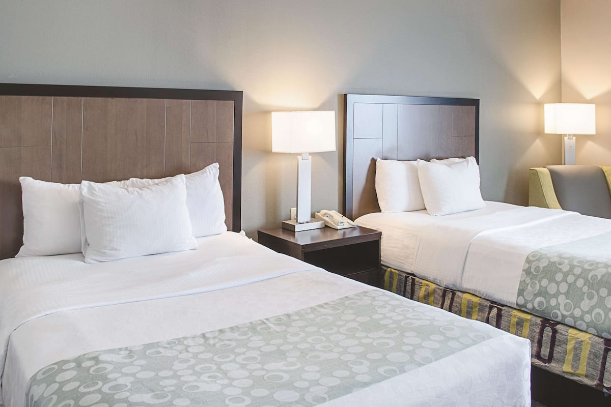 Une chambre d’hôtel avec deux lits, chacun doté d’une tête de lit, de tables de chevet avec des lampes et d’une couvre-lit à motifs.
