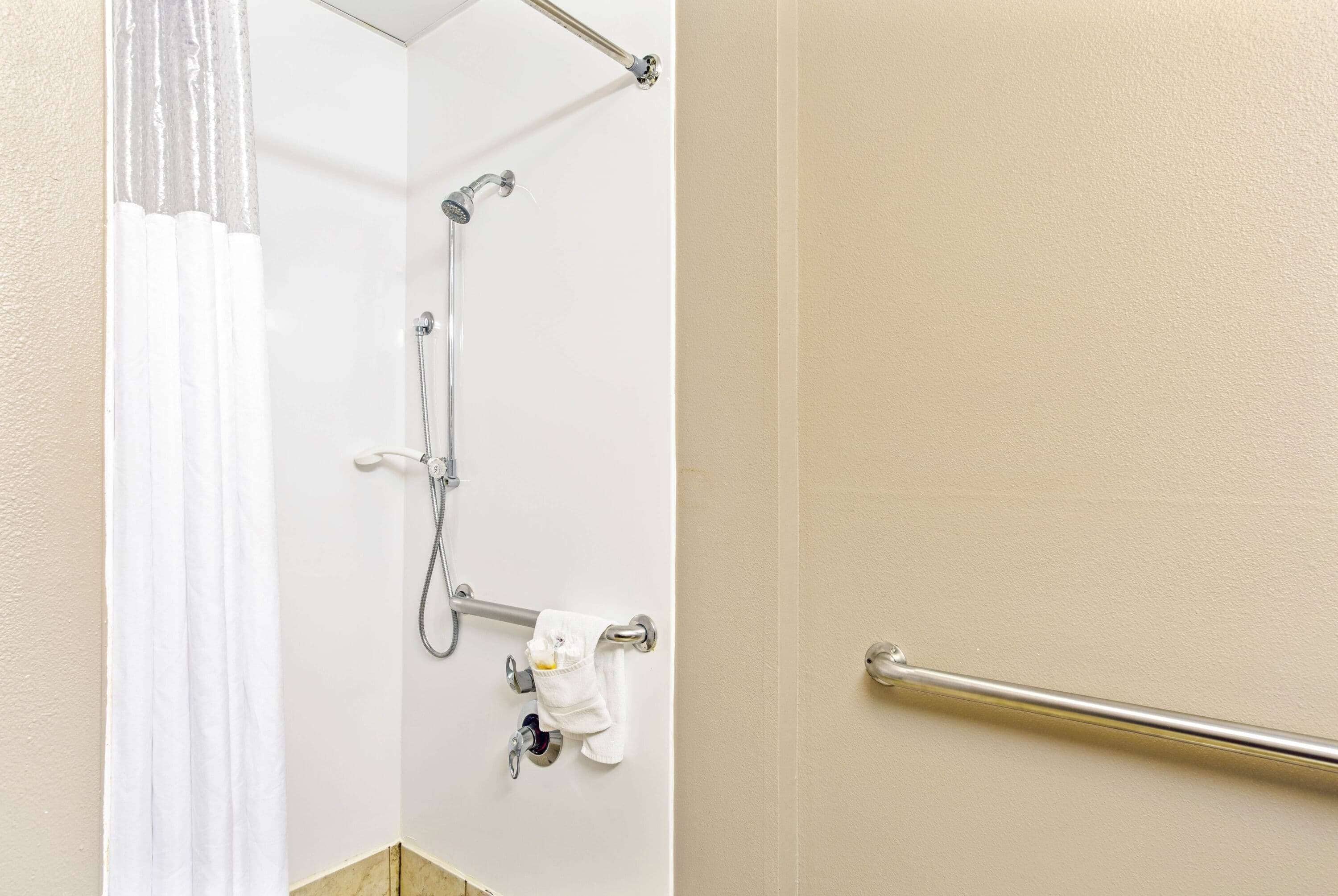 Un bagno con doccia, porta asciugamani e barra di sostegno.