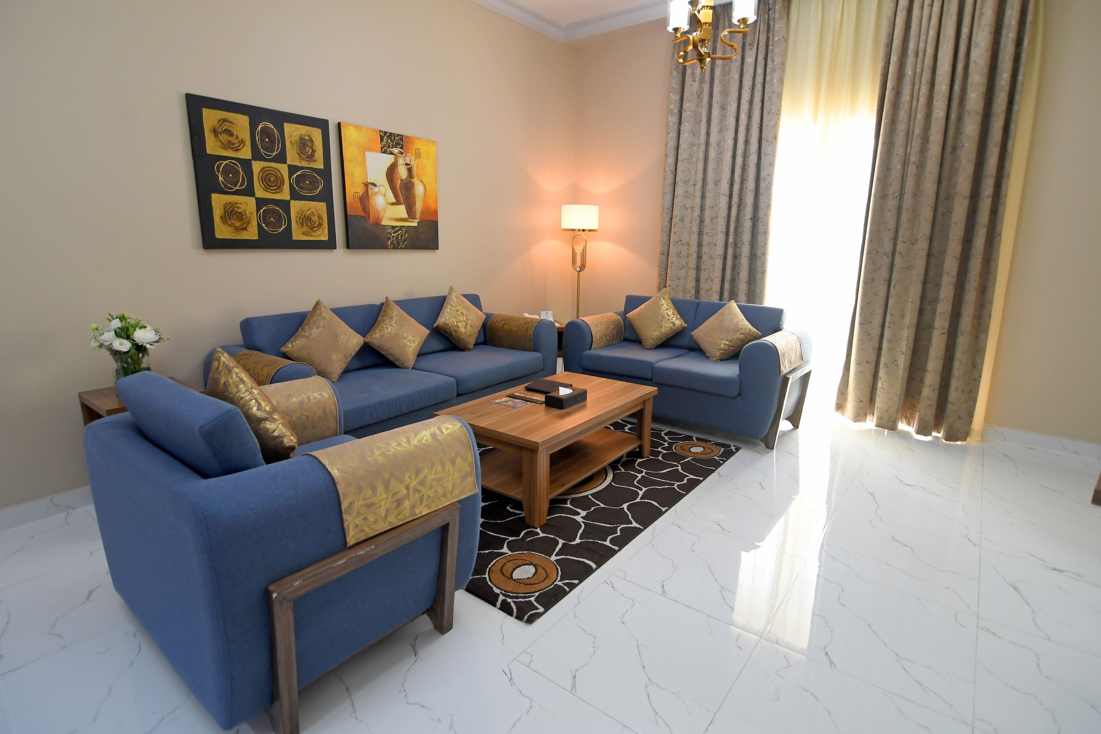 A living room with a blue sofa set, a wooden coffee table, a floor lamp, and a patterned rug.