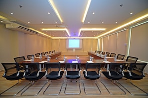 A conference room with a long table, chairs, and a projector screen.