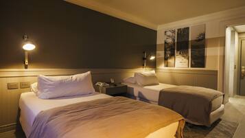 Une chambre d’hôtel avec deux lits, une table de chevet et une lampe fixée au mur.