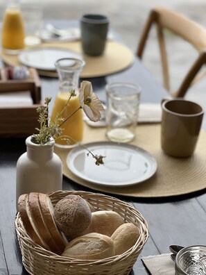 A breakfast setting with bread, a glass of juice, and a vase with dried flowers. - Hotel Costaustralis (Natales)
