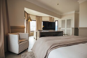 Una habitación de hotel con una cama grande, televisión, escritorio y una silla.
