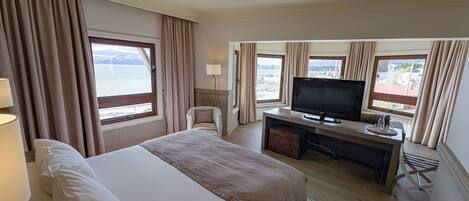 Una habitación de hotel con una cama, un escritorio con televisor y vista al mar.
