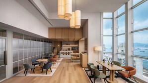Ein modernes Interieur mit einem langen Essbereich, einer Küche und großen Fenstern mit Blick auf das Meer.