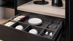 Eine moderne Küche mit integrierter Kaffeemaschine, Wasserkocher und Schubladenorganizer für Teller und Schüsseln.